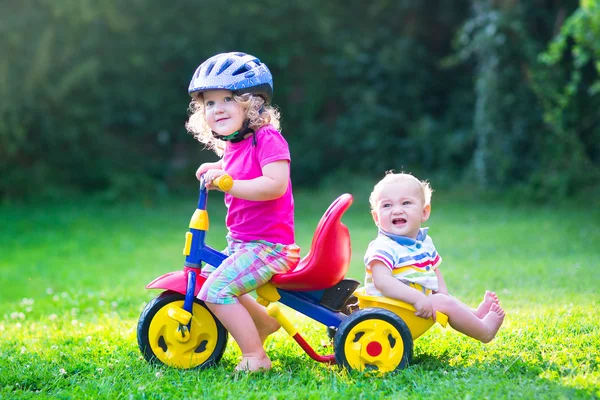 Двое детей на велосипеде в саду — стоковое фото