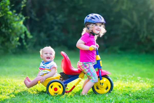 Duas crianças de bicicleta no jardim — Fotografia de Stock