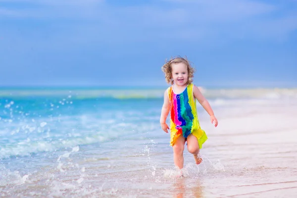 Klein meisje wordt uitgevoerd op een strand — Stockfoto