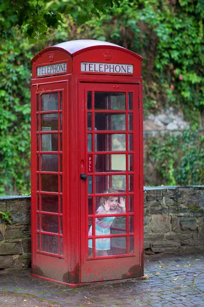 Niña en una cabina telefónica — Foto de Stock