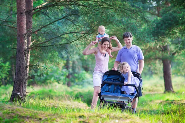 Senderismo de padres activos con dos niños en un cochecito — Foto de Stock