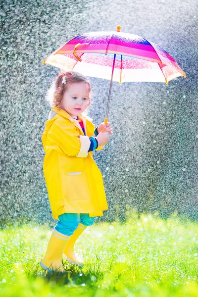 Lustiges Kleinkind mit Regenschirm spielt im Regen — Stockfoto