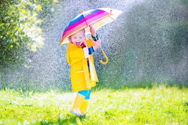 Lustiges Kleinkind mit Regenschirm spielt im Regen — Stockfoto