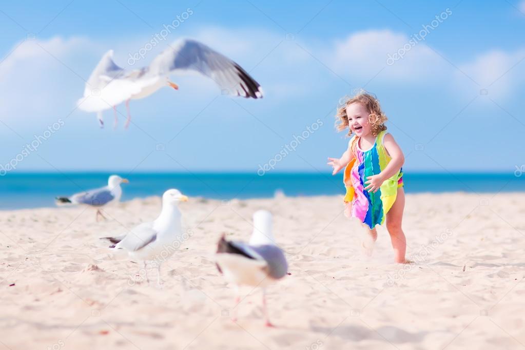 Little girl playing with seagulls