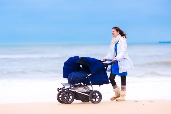 Moeder met dubbele kinderwagen op een strand — Stockfoto