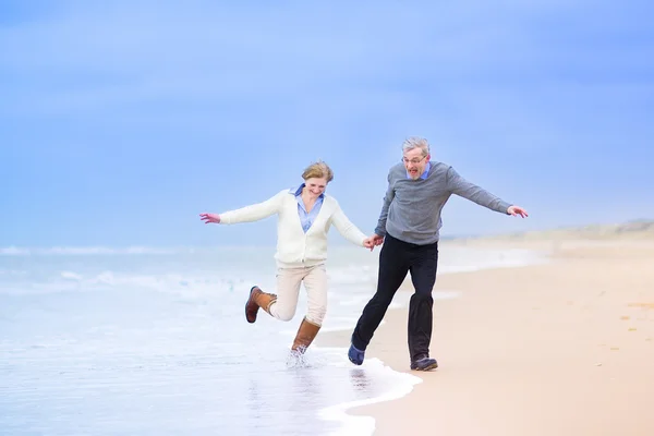 Midden leeftijd paar draait op een strand — Stockfoto