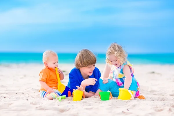 Üç çocuk kumsalda oynarken — Stok fotoğraf