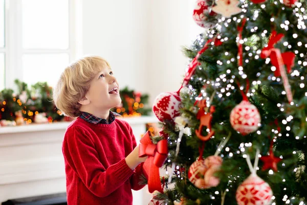 自宅でクリスマスを飾る子供 クリスマスの朝に贈り物やプレゼントを開く ニットのセーターに身を包んだ男の子 冬休みを祝う家族 子供たちはリビングルームと窓を飾る — ストック写真