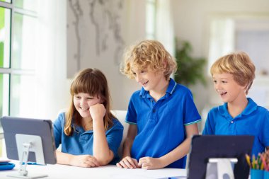Çevrimiçi uzaktan öğrenme. Bilgisayarlı okul çocukları öğretmen ve sınıf grubuyla görüntülü konuşma yapıyorlar. Çocuk evden ders çalışıyor. Karantina ve koronavirüs salgını sırasında evde eğitim.