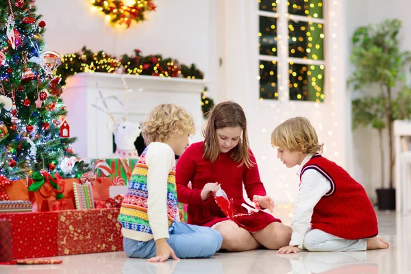 Børn Ved Juletræ Pejs Juleaften Familie Med Børn Fejrer Jul - Stock-foto