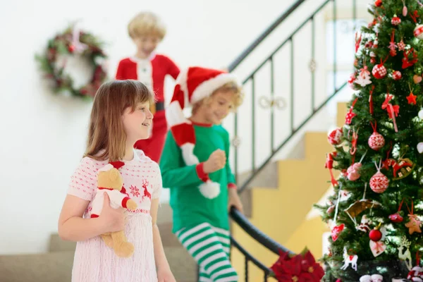 圣诞节早上 孩子们在楼梯上奔跑 穿着睡衣的孩子们跑下楼去 急于打开圣诞礼物 在家里庆祝 男孩和女孩打开礼物 — 图库照片