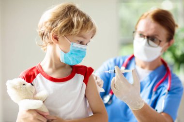 Covid-19 aşısı olan bir çocuk. Genç çocuklar için koronavirüs aşısı. Doktor hastaya covid iğnesi yapıyor. Ergenler ve çocuklar için bağışıklık programı. Sağlık hizmetleri. Çocuk doktorundaki çocuk..
