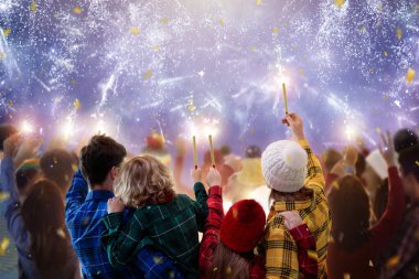 Mutlu yıllar. Aile havai fişek izliyor. Aileler ve çocuklar 2022 yılını kutluyorlar. Kış tatili kalabalık partisi. Açık hava eğlencesi. Çocuklar, anne ve baba havai fişek gösterisi izleyecek..