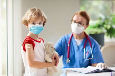 Covid-19 aşısı olan bir çocuk. Genç çocuklar için koronavirüs aşısı. Doktor hastaya covid iğnesi yapıyor. Ergenler ve çocuklar için bağışıklık programı. Sağlık hizmetleri. Çocuk doktorundaki çocuk..