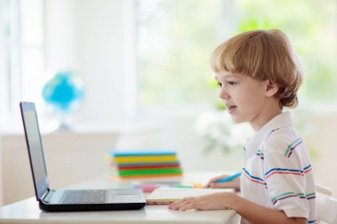 Çevrimiçi uzaktan öğrenme. Bilgisayarlı okul çocukları öğretmen ve sınıf grubuyla görüntülü konuşma yapıyorlar. Çocuk evden ders çalışıyor. Karantina ve koronavirüs salgını sırasında evde eğitim.