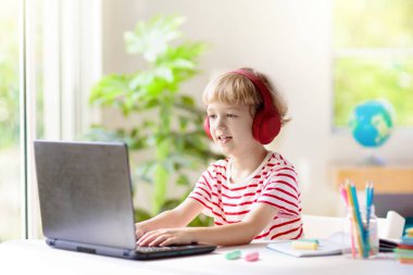 Çevrimiçi uzaktan öğrenme. Bilgisayarlı okul çocukları öğretmen ve sınıf grubuyla görüntülü konuşma yapıyorlar. Çocuk evden ders çalışıyor. Karantina ve koronavirüs salgını sırasında evde eğitim.