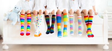 Renkli gökkuşağı çorapları giyen çocuklar. Çocuk ayakkabısı koleksiyonu. Diz boyu çorap ve tayt çeşitleri. Çocuk giysisi ve giysisi. Çocuk modası. Küçük erkek ve kız grubunun bacakları ve ayakları.