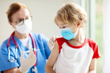 Covid-19 aşısı olan bir çocuk. Genç çocuklar için koronavirüs aşısı. Doktor hastaya covid iğnesi yapıyor. Ergenler ve çocuklar için bağışıklık programı. Sağlık hizmetleri. Çocuk doktorundaki çocuk..
