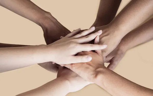 joined hands of multiethnic women, beige background