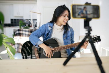 Vlogger denen kadın gitar çalmayı ve şarkı söylemeyi öğretiyor, evden, tele-çalgıcı gitar öğretmeni.