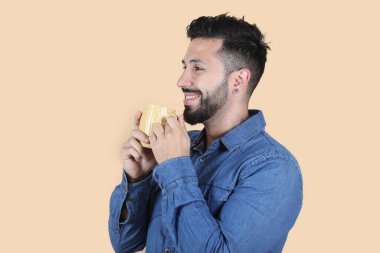 Çekici Latin bir adam elleriyle bardak tutuyor.