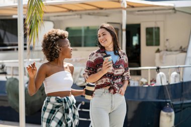 Kahve ve turizm içerken çok ırklı arkadaşlar şehirde yürürken konuşuyorlar.