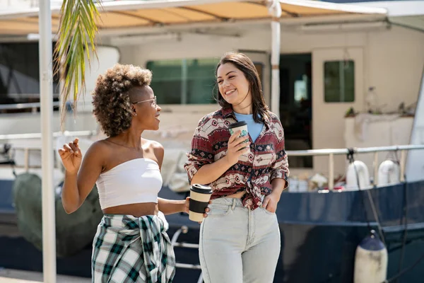 Kahve ve turizm içerken çok ırklı arkadaşlar şehirde yürürken konuşuyorlar.