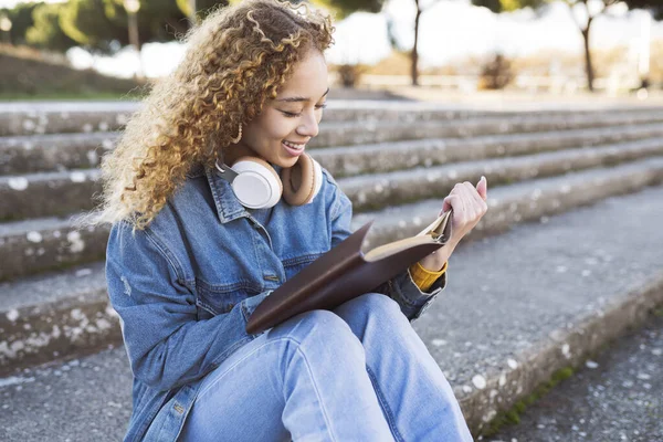 Pretty Hispanic Curly Haired Woman Sitting Stairs Park Reading Book — Φωτογραφία Αρχείου