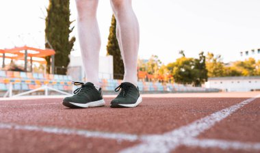 Atletin ayaklarının koşu pistinde yakın plan çekimi.