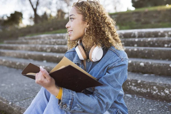 Кучерявий Іспаномовний Жінка Читає Книгу Сходах Парку Джинсовим Одягом Навушниками — стокове фото