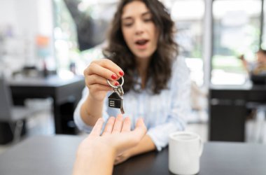 Ev satın alma sözleşmesinin imzalanması, ev satışı yapan kadının yeni evinin anahtarlarını alması, anahtarlarla yaklaşması - anahtar devir konsepti -