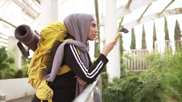 带有头巾的漂亮的穆斯林妇女画像 背着背包的游客用手机交谈 阿拉伯妇女旅行 — 图库视频影像
