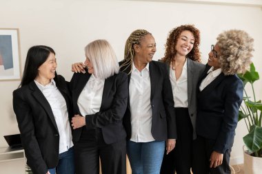 Farklı nesillerden bir grup iş kadını ofiste konuşuyor. Çok ırklı çalışan kadınlar - kadınların güçlendirilmesi kavramı -