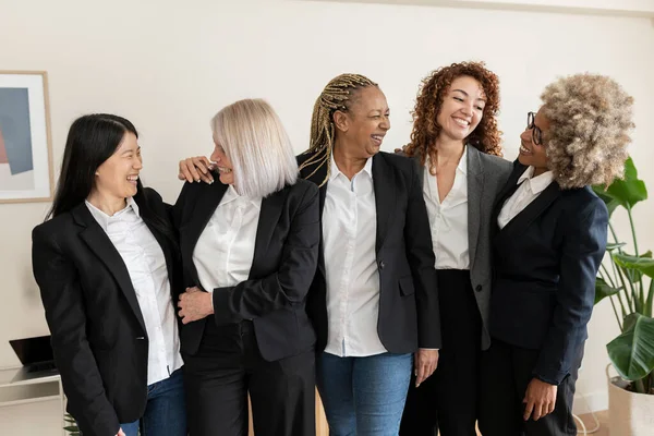 Farklı nesillerden bir grup iş kadını ofiste konuşuyor. Çok ırklı çalışan kadınlar - kadınların güçlendirilmesi kavramı -