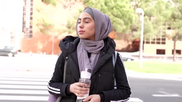 穆斯林妇女在十字路口的街上喝水 头戴头巾的妇女在户外喝水 女运动员的概念 — 图库视频影像
