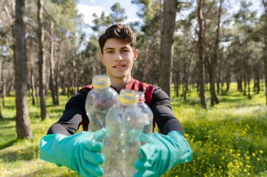 Mavi gözlü yakışıklı sarışın gönüllü plastik toplama, geri dönüşüm konsepti.