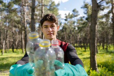 Çevreyle ilgilenmek için ormanda plastik çöpleri öğreten adam. Geri dönüşüm kavramı. -