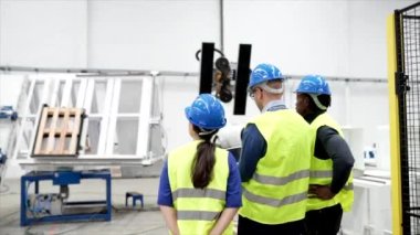Mühendisler fabrikadaki endüstriyel robotların çalışma sürecini kontrol ediyorlar.