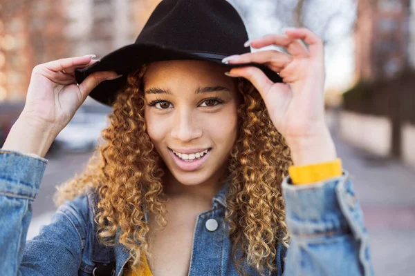 pretty happy hispanic woman with curly hair wearing a hat in the city old woman concept