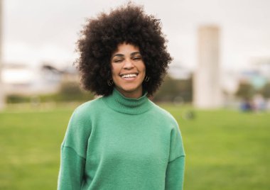 Oldukça mutlu kıvırcık saçlı Afro-Amerikan kadın açık hava parkında gülümsüyor çeşitlilik yaşam tarzı konsepti-