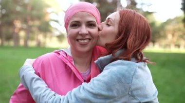 Kanserden kurtulan pembe fularlı kadın arkadaşına sarılıyor, kanser tedavisi görüyor, göğüs kanseriyle savaşıyor.
