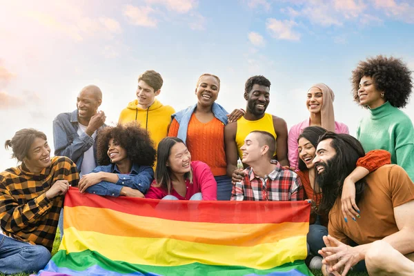 Bir grup farklı genç dışarıda eğleniyor ve gay bayrağı protesto ederek gülüyorlar.