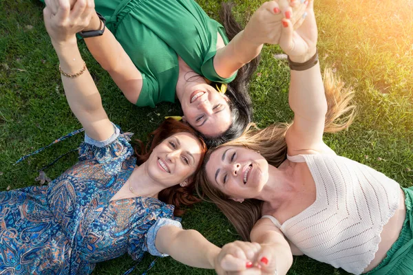 Grupo Três Mulheres Maduras Deitado Grama Olhando Para Cima Feliz — Fotografia de Stock