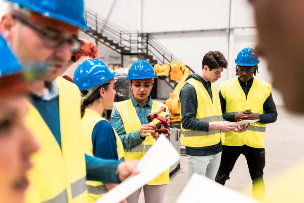 group of multiracial workers in protective helmet assembly engineers robotics factory