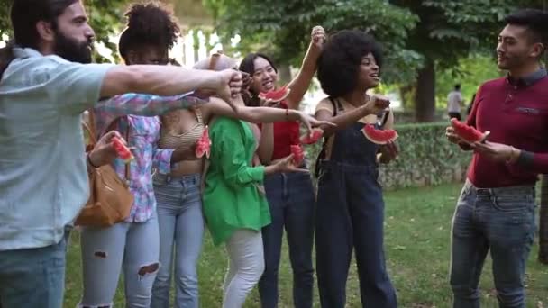 Группа Многорасовых Друзей Питающихся Арбузом Парке Освистывают Своего Азиатского Друга — стоковое видео