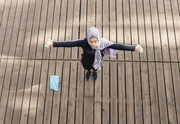 muslim woman doing sports with dumbbells, arab woman fitness concept overhead shot