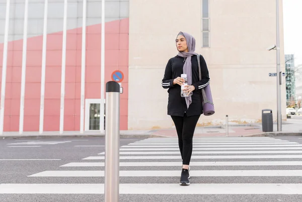 Mujer Musulmana Ropa Deportiva Cruzando Calle Ciudad Con Botella Agua —  Fotos de Stock