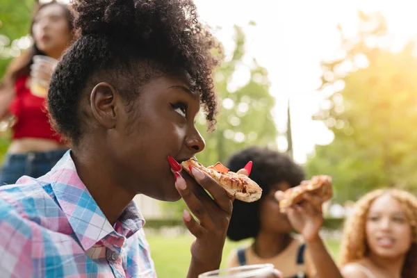 friends eat pizza in the park, focus african woman eating