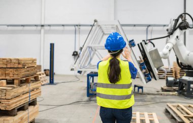 woman engineer using robotic machinery in factory