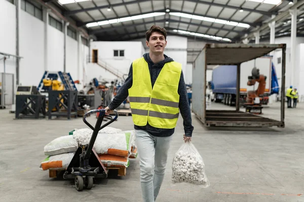 Portrait of warehouse staff man carrying load with a hand truck.